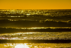 Sunset reflects off relentless waves washing the shoreline. Ruby Beach, Olympic National Park, Washington.